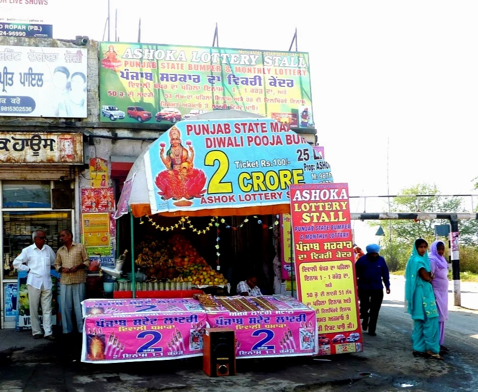 An Indian lottery stall with colorful Punjab lottery signs and printed ticket displays.